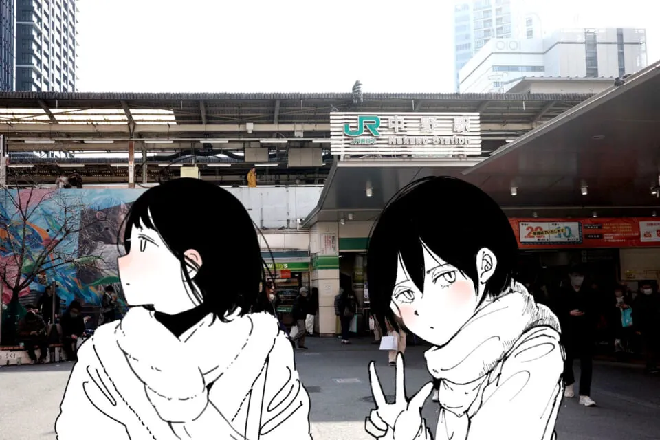 カメラを持つ二人の女性が駅前に立つ