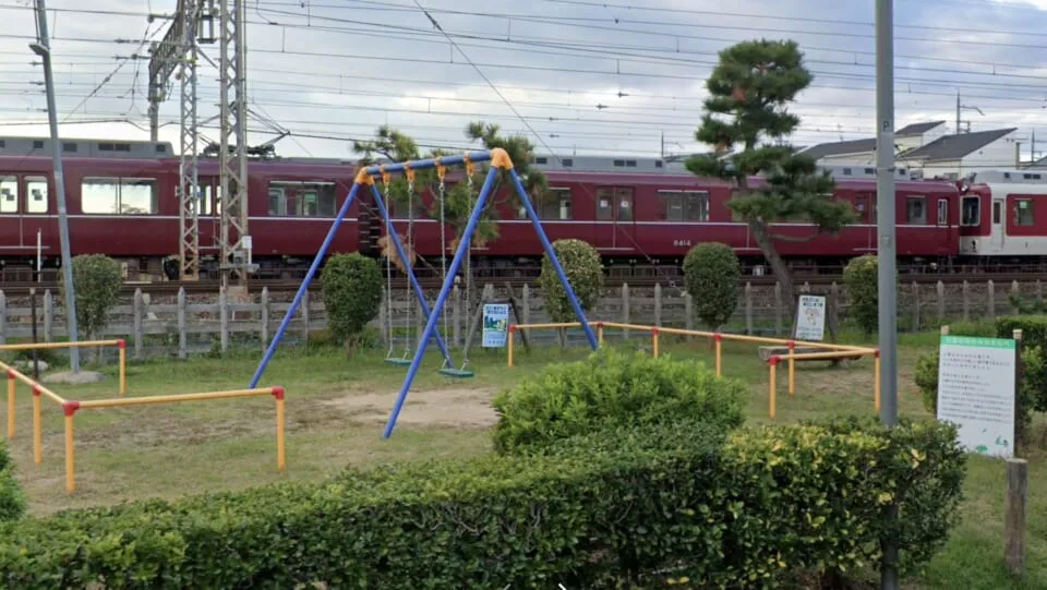 線路沿いの公園にある青いブランコと赤い電車